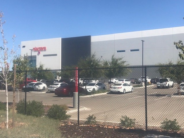 Large bottling plant exterior wall painted white with dark gray accent panel