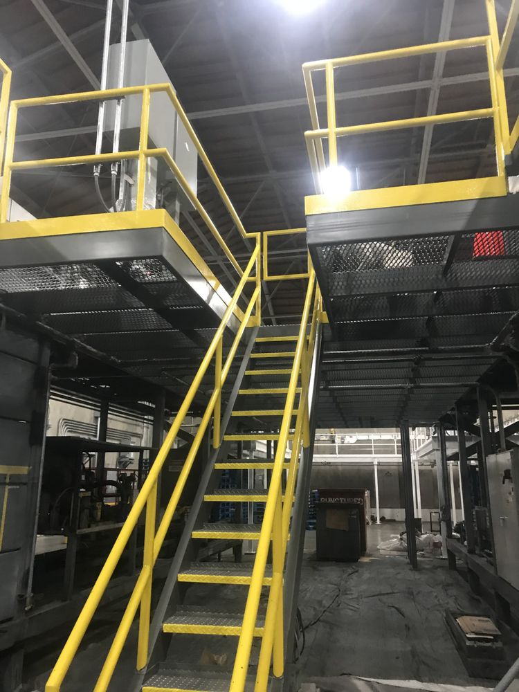 Interior plant mezzanine with safety-yellow handrails and gray coated steel platforms