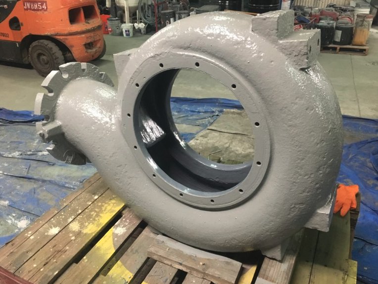 Large pump volute casing coated gray on a pallet inside the shop