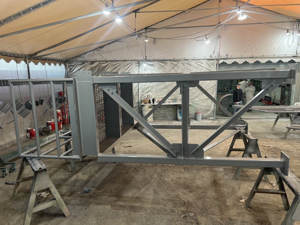 Structural steel truss coated gray inside a covered shop paint area