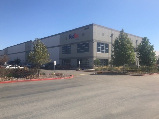 Distribution facility exterior painted in two-tone gray with tenant signage